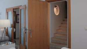 Hotellihuone, jossa on puinen ovi, peili, lamppu ja portaikko.