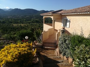 A house with a tiled roof, a covered patio, and a view of mountains. - Résidence Marina Di A Testa (Zonza)