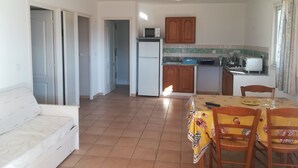 Un espacio habitable compacto con kitchenette, comedor y sofá.