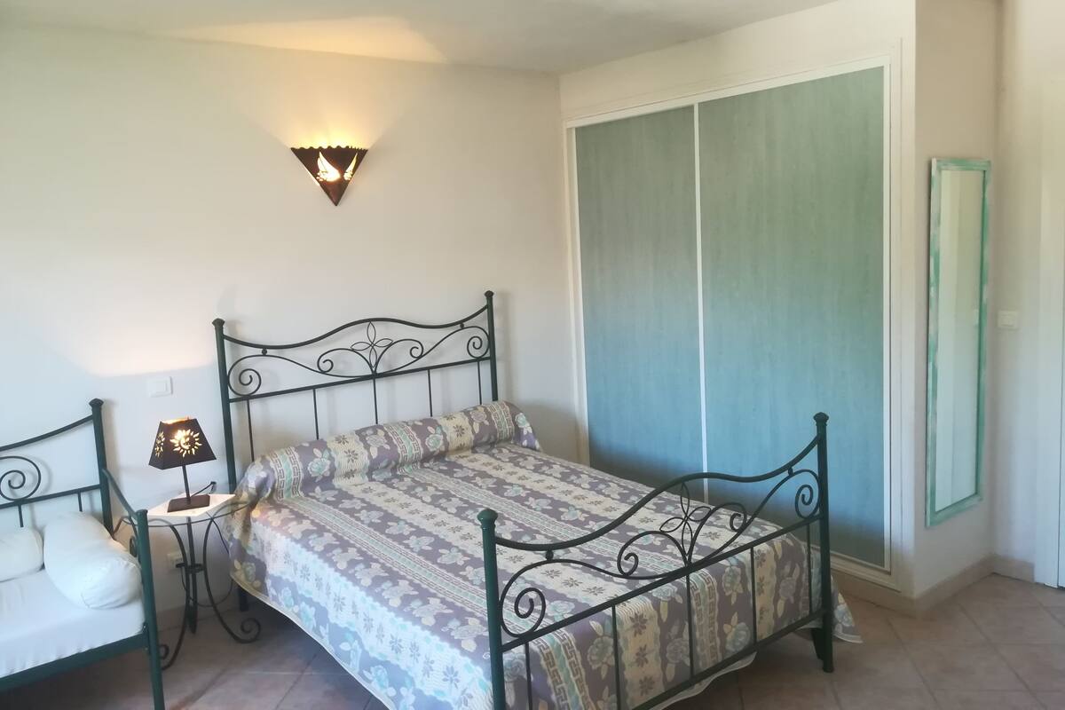 A bedroom with a bed, a nightstand, a wall-mounted lamp, and a wardrobe.