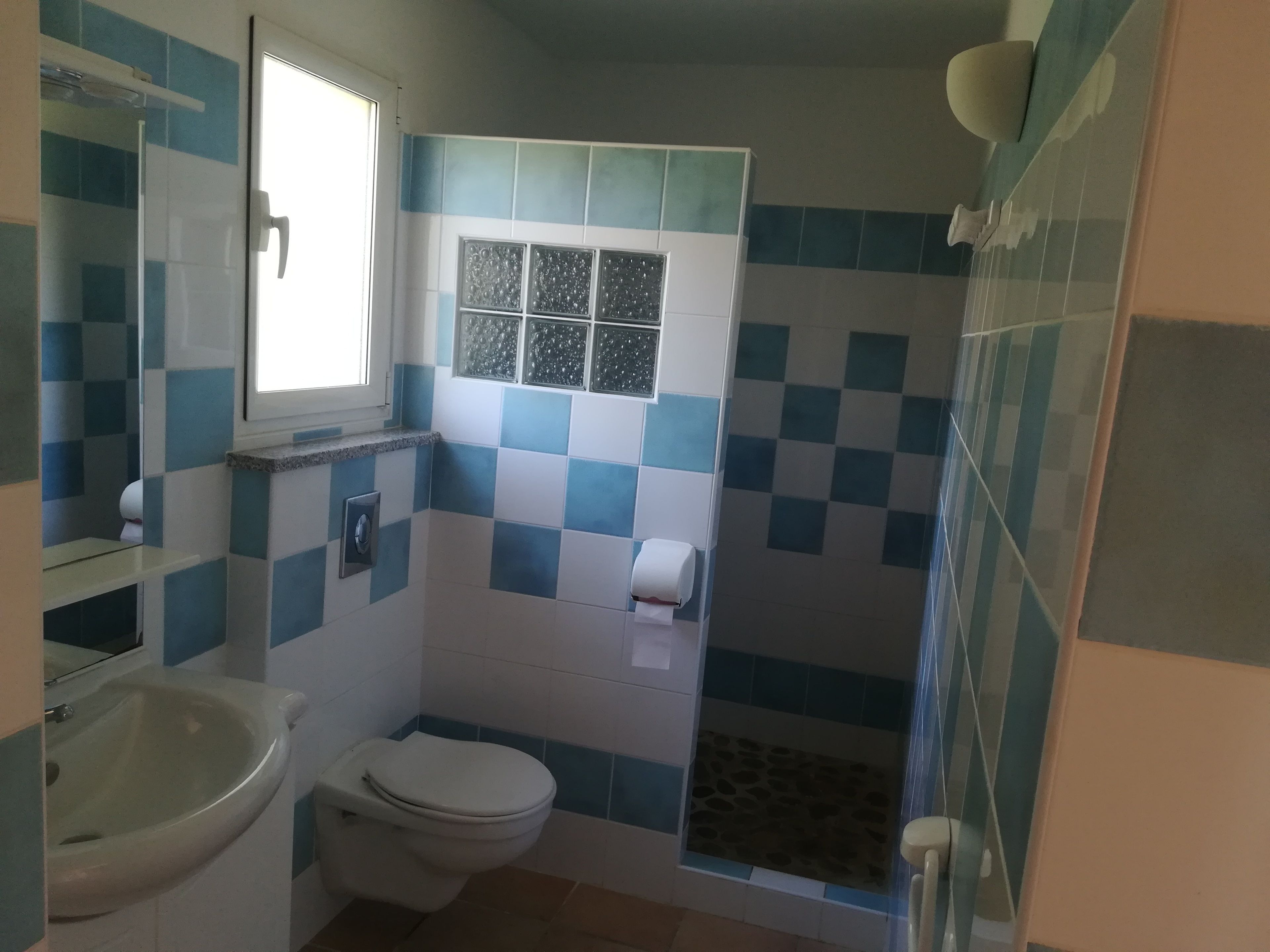 Une salle de bain comprenant des toilettes, un lavabo et un espace douche.