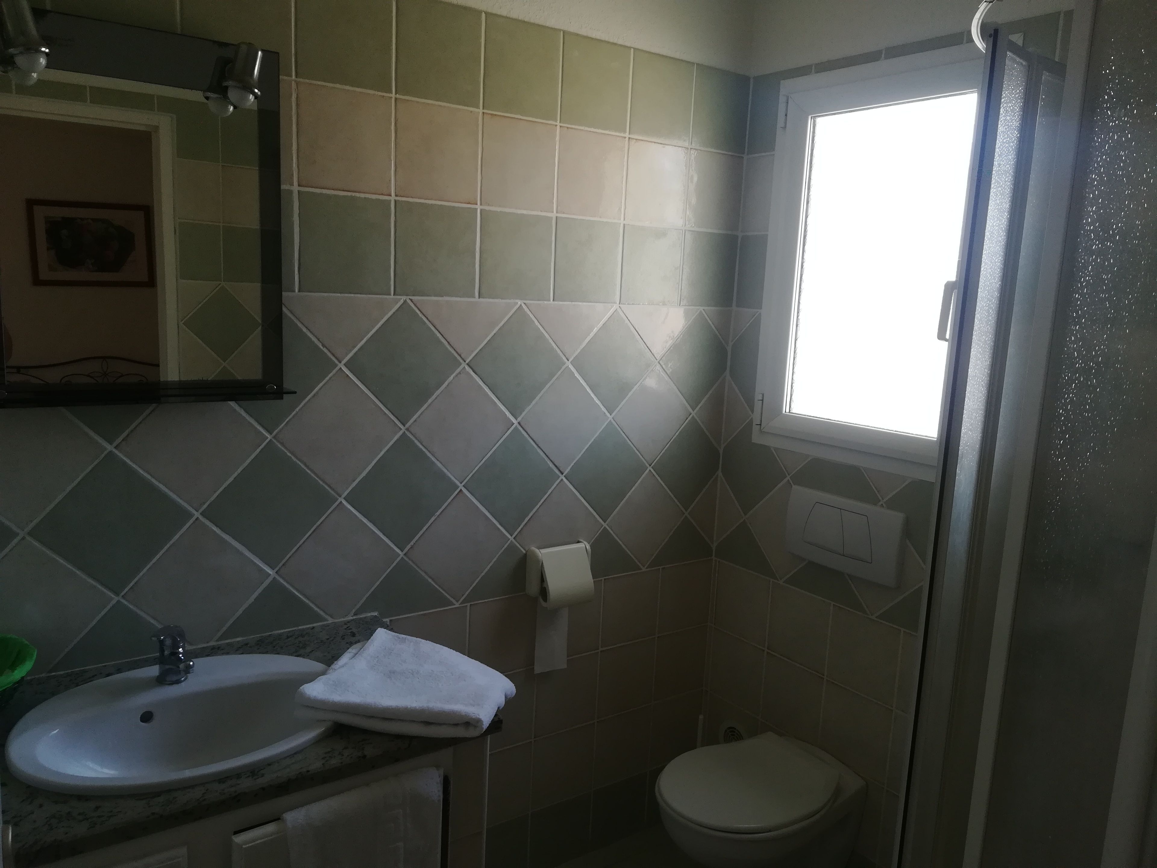Un baño con lavamanos, espejo y retrete.