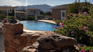 Una piscina con paredes de piedra y vistas a montañas al fondo.