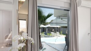 A modern room with a sliding glass door leading to a pool area with lounge chairs and umbrellas. - Villa N Drage with pool  (Nin)