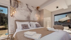 A modern bedroom with a large bed, a glass table, and a view of the outdoors. - Villa N Drage with pool  (Nin)