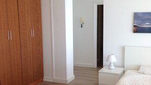 A bedroom with a bed, nightstand, lamp, and a wooden wardrobe.