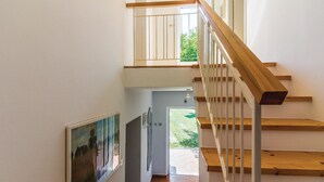 Una escalera de madera con barandillas blancas que conduce a un espacio exterior con vistas a zonas verdes.