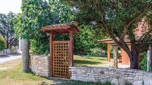 Un muro de piedra con una puerta de madera y una estructura de pérgola.