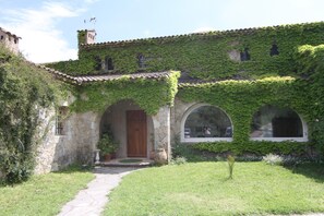 A stone building with a tiled roof, ivy-covered walls, and a central wooden door. - The house in the woods with swimming pool between Verdon and the Mediterranean (Trans-en-Provence)