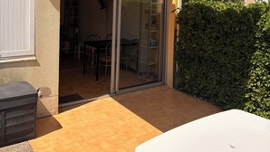A residential building with a balcony, a sliding glass door entrance, and a small outdoor seating area.