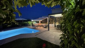 Un jardin avec une piscine, du mobilier d’extérieur et un patio couvert.
