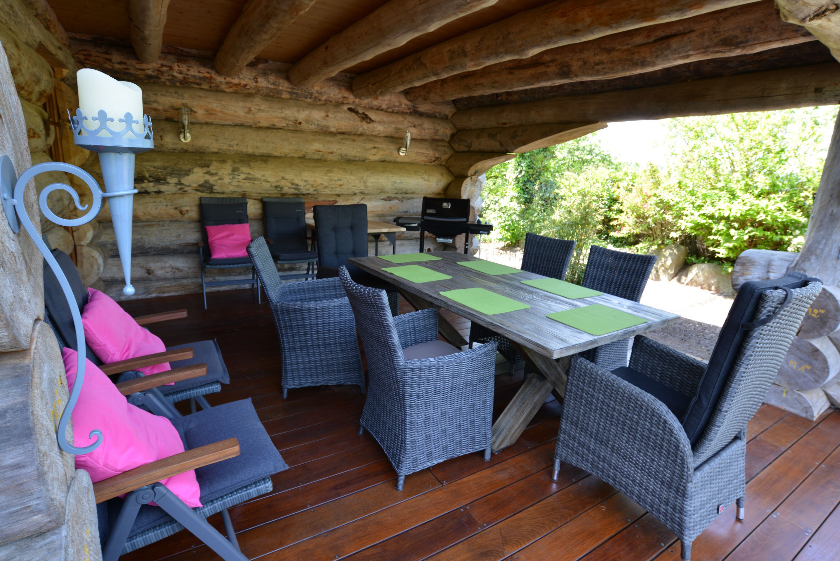 An outdoor wooden deck with wicker furniture, a table, and a grill.