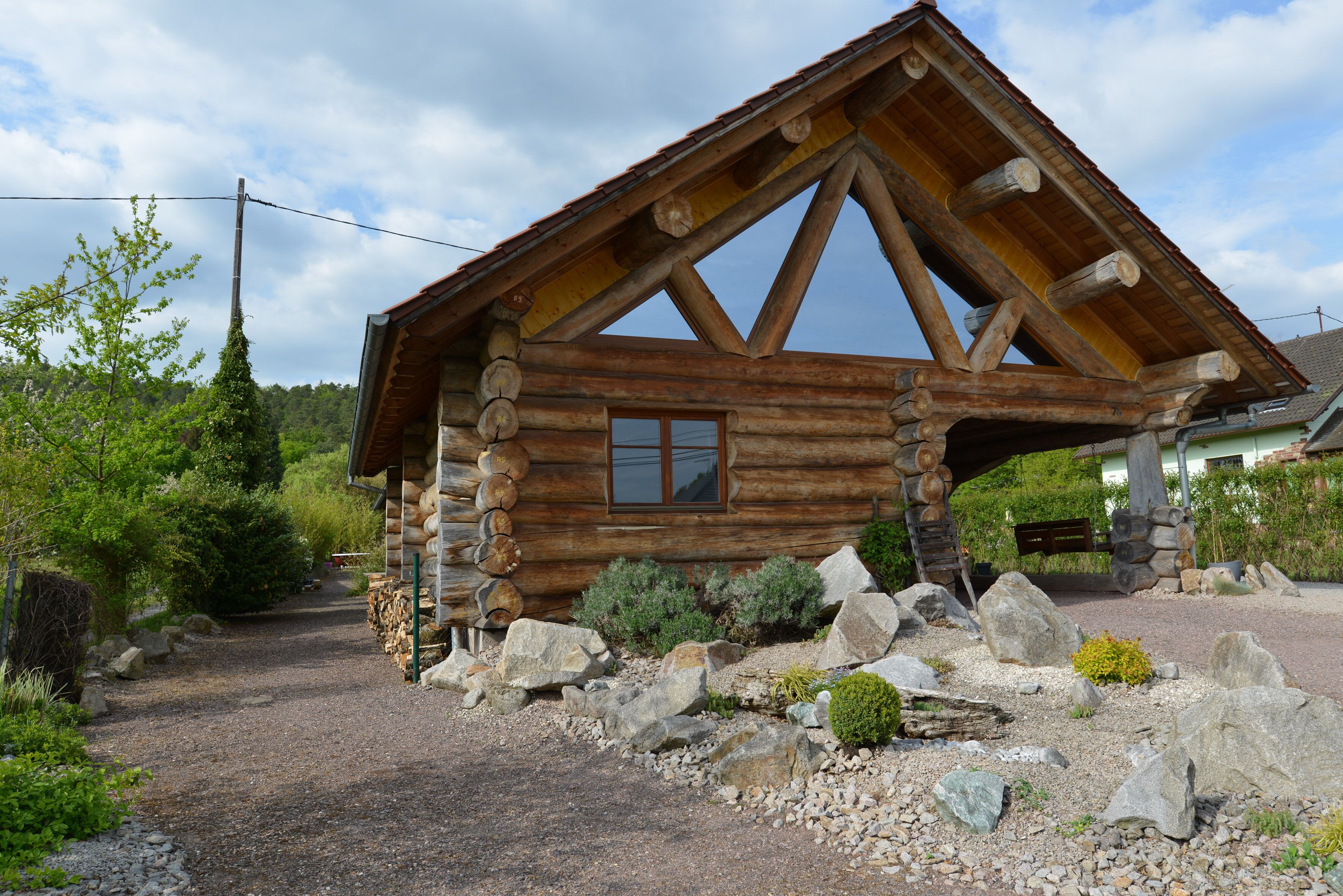 A log cabin with a pitched roof, a window, and a stone foundation.
