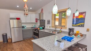 A modern kitchen with granite countertops, stainless steel appliances, and bar stools.