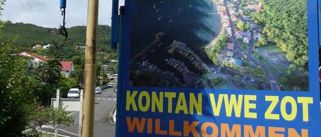 A welcome sign for Deshaies with a scenic view of a coastal town.