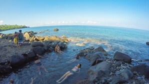 A rocky beach with clear water and a distant shoreline. - Holiday rental "AUTHENTICITY and CONVIVIALITY" in DESHAIES GUADELOUPE (Deshaies)