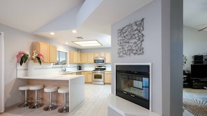 A modern kitchen with a central island, bar stools, a microwave, oven, and a fireplace. - Desert Pool Oasis located in the heart of Las Cruces (Las Cruces)