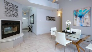 A modern dining area with a glass table, white chairs, a black tray, and a vase of white flowers. - Desert Pool Oasis located in the heart of Las Cruces (Las Cruces)