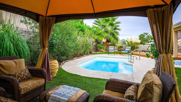 A covered outdoor area with a pool, wicker furniture, and a view of the surrounding garden. - Desert Pool Oasis located in the heart of Las Cruces (Las Cruces)