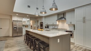 A spacious kitchen with a large island, stainless steel appliances, and pendant lighting.