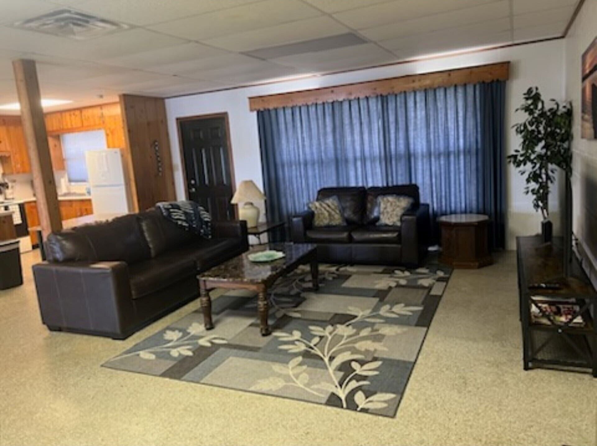 Ein Wohnzimmer mit einem dunkelbraunen Ledersofa, einem Couchtisch und einem Teppich mit Muster.