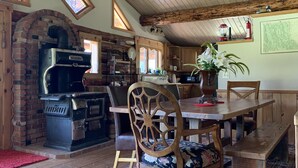 Une cuisine rustique avec un four en briques, des meubles en bois et un coin repas avec une banquette.