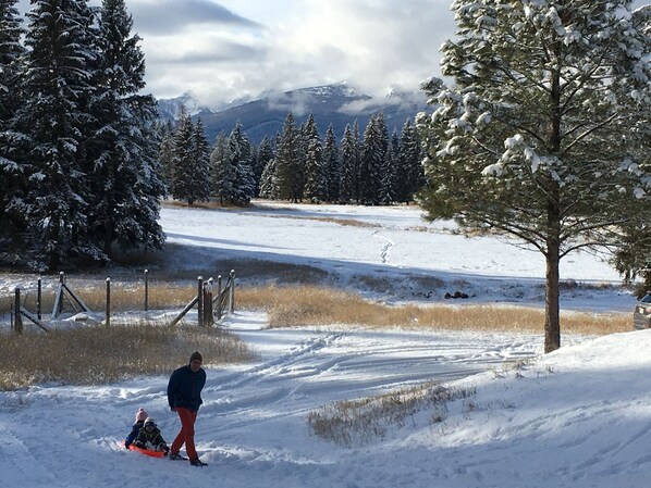 Paisaje nevado con una persona y un niño deslizándose en un trineo.