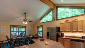 A kitchen with a large island, wooden cabinets, a refrigerator, and a dishwasher. - The Ridge Chalet, an A-Frame Killington Home (Killington)