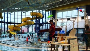 Ein Hallenbad mit mehreren Bahnen, Wasserrutschen und einem Rettungsschwimmerstand.