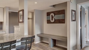Uma cozinha moderna com bancada de mármore, um banco embutido e uma grande decoração em formato da letra 'C' na parede.