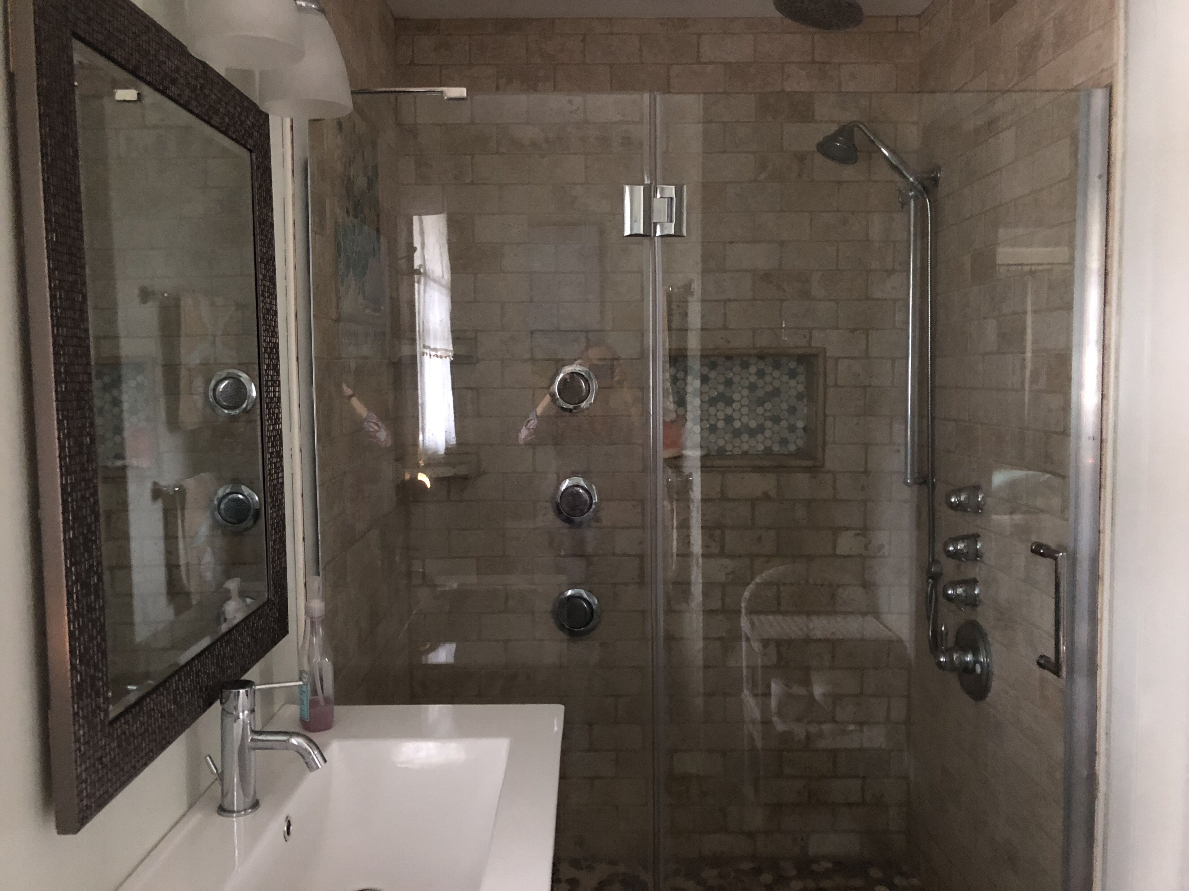 Un bagno moderno con doccia vetrata, lavandino bianco e uno specchio grande.