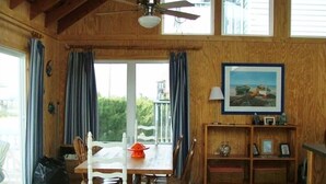 A dining area with a wooden table and chairs, a ceiling fan, and a view through a glass door. - Ocean Block Single Family Home - Open floor plan & pet friendly! (Dewey Beach)