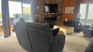A cozy living room with a stone fireplace, a flat-screen TV, and comfortable seating. - Ocean Block Single Family Home - Open floor plan & pet friendly! (Dewey Beach)