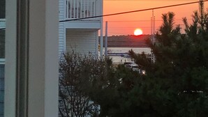 A multi-story building with balconies, a sunset in the background, and power lines overhead. - Ocean Block Single Family Home - Open floor plan & pet friendly! (Dewey Beach)