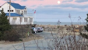 A coastal building with a blue roof, a flag, and a parking area. - Ocean Block Single Family Home - Open floor plan & pet friendly! (Dewey Beach)
