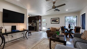 A modern living room with a flat-screen TV, a ceiling fan, and a dining area with a table and chairs. - Private Phoenician Sanctuary- Villa De Paz (Phoenix)