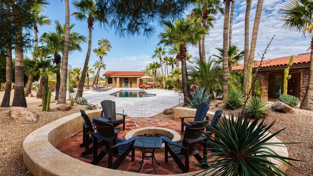 A pool area with a fire pit and seating, surrounded by palm trees and cacti. - Private Phoenician Sanctuary- Villa De Paz (Phoenix)