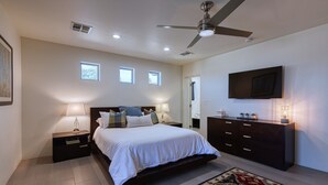 A bedroom with a bed, nightstands, a dresser, a television, and a ceiling fan. - Private Phoenician Sanctuary- Villa De Paz (Phoenix)