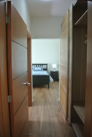 A bedroom with a bed, bedside table, lamp, and wooden wardrobe.