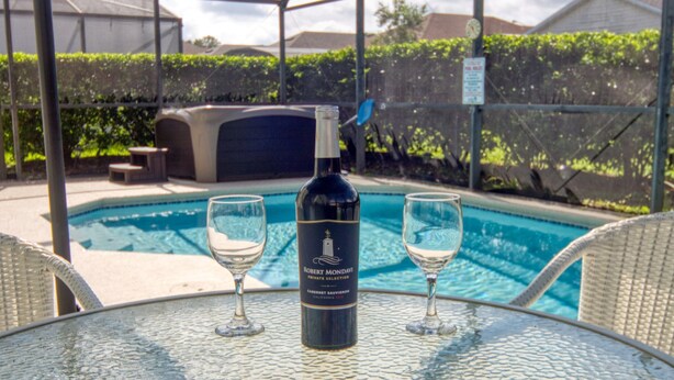 A poolside table with a bottle of wine and two glasses. - Windsor Palms Villa w/South Facing Private Pool & Hot Tub Close to Disney & Golf (Kissimmee)