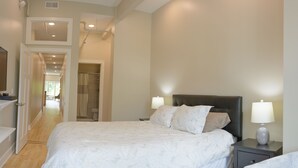 Un dormitorio con una cama grande, lámparas de noche y una mesita.