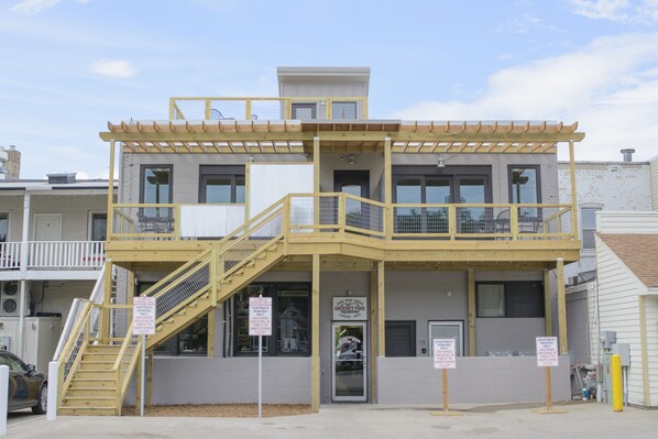 A multi-story building with a balcony, a staircase, and multiple signs indicating parking restrictions.