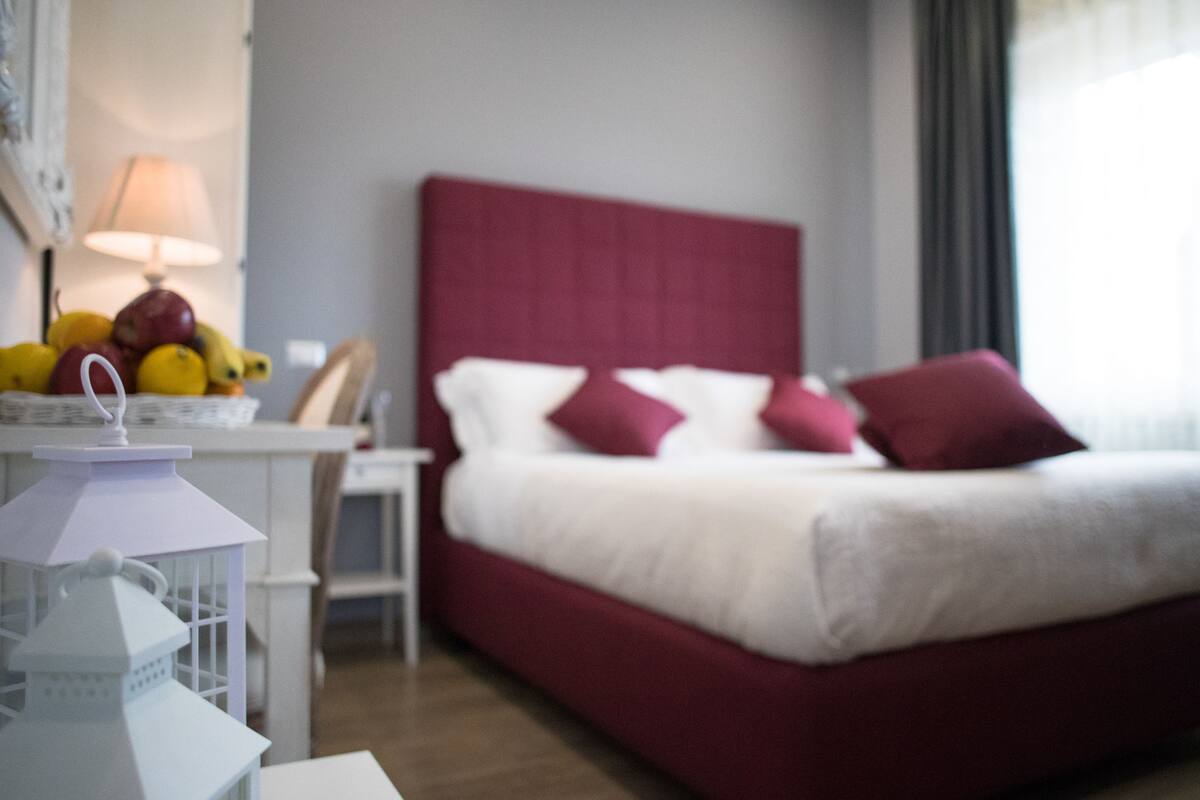 A hotel room with a bed, a nightstand, a lamp, and a fruit basket.