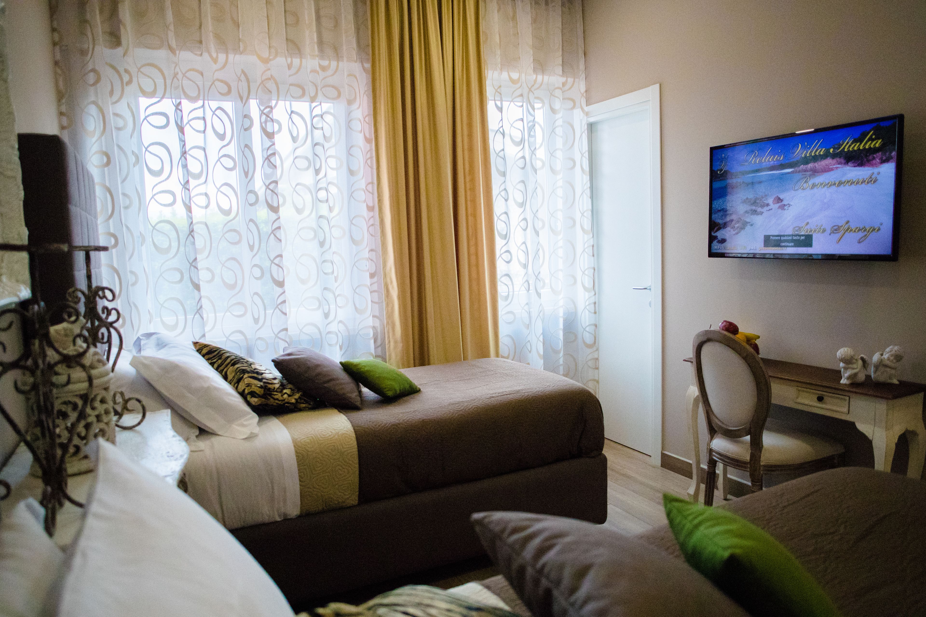 A hotel room with two beds, a television on the wall, and a desk with a chair.
