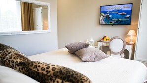 A hotel room with a bed, a television displaying a scenic view, a desk with a lamp, and a chair. - Relais Villa Italia (Rome)