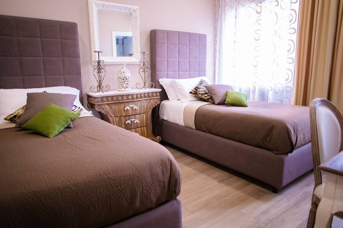 A hotel room with two beds, a wooden dresser, and a mirror.