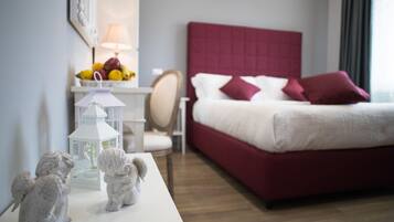 A hotel room with a bed, a bedside table with a lamp, a fruit bowl, and two angel figurines.