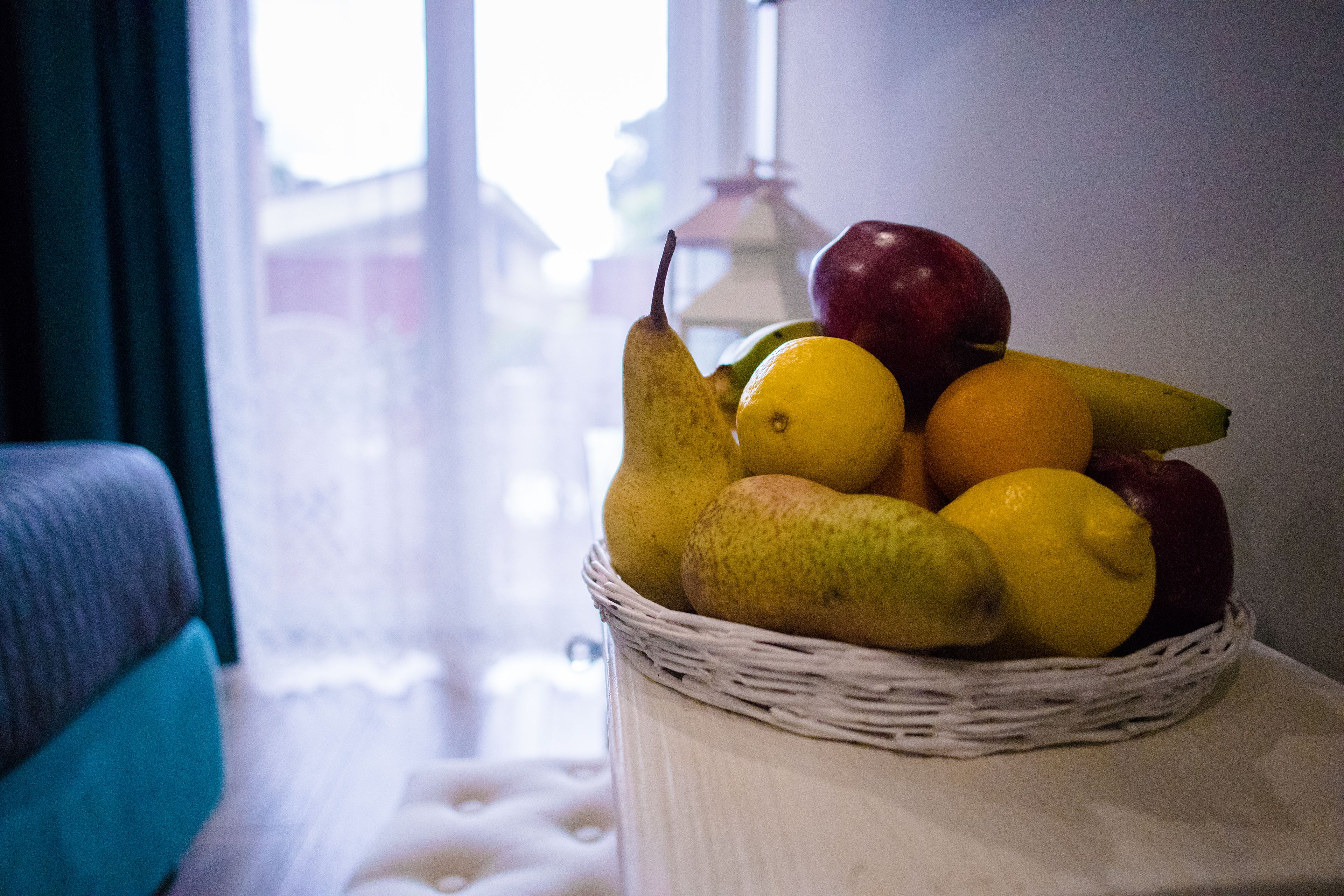 Een rieten mand gevuld met fruit op een witte tafel.
