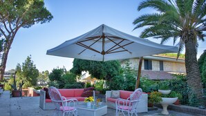 An outdoor patio with wicker furniture, a large umbrella, and potted plants. - Relais Villa Italia (Rome)