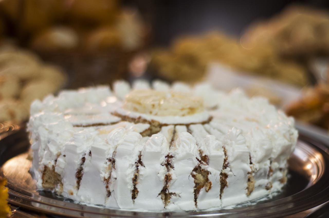 A cake with white frosting and a central decoration on a silver platter.